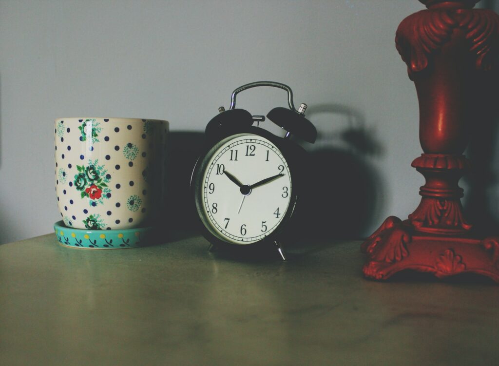 black table clock beside ceramic vase