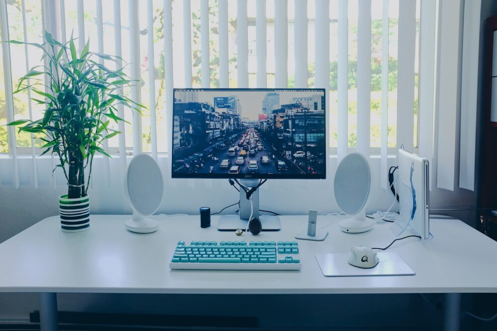 black flat screen computer monitor; keyboard; speakers; mouse on desk