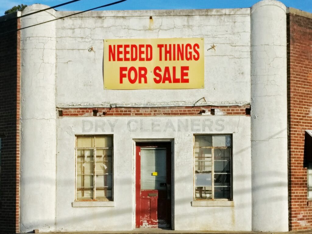 needed things for sale poster posted on white concrete establishment