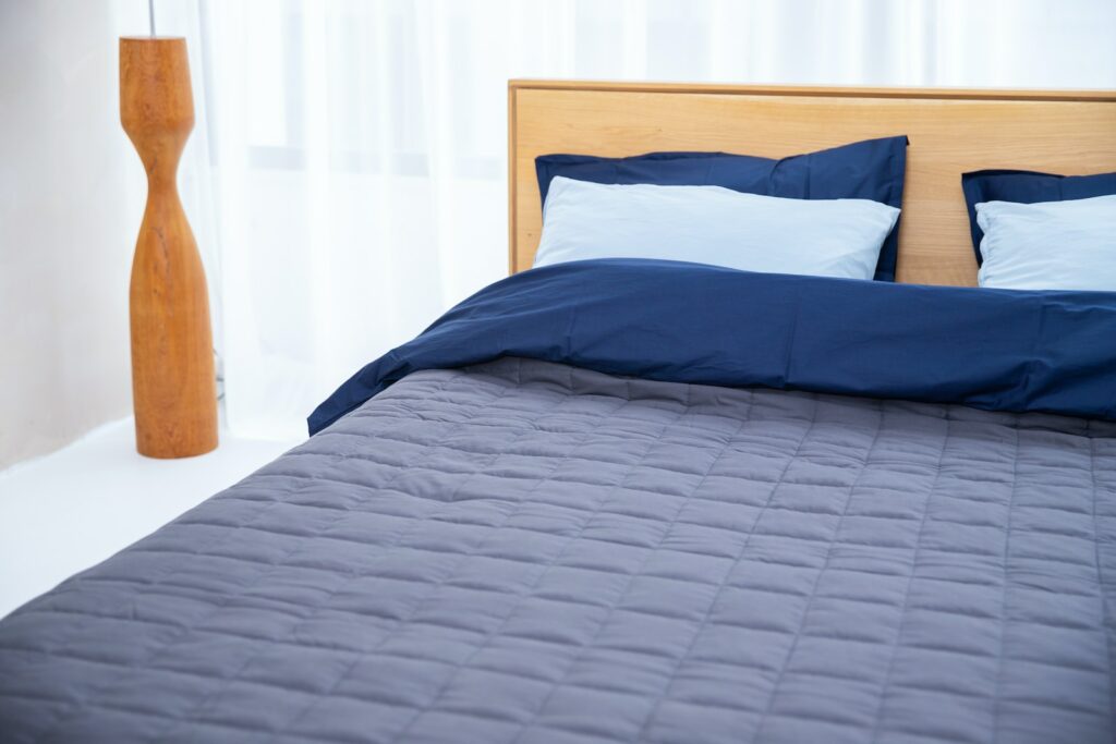 a bed with a blue comforter and pillows