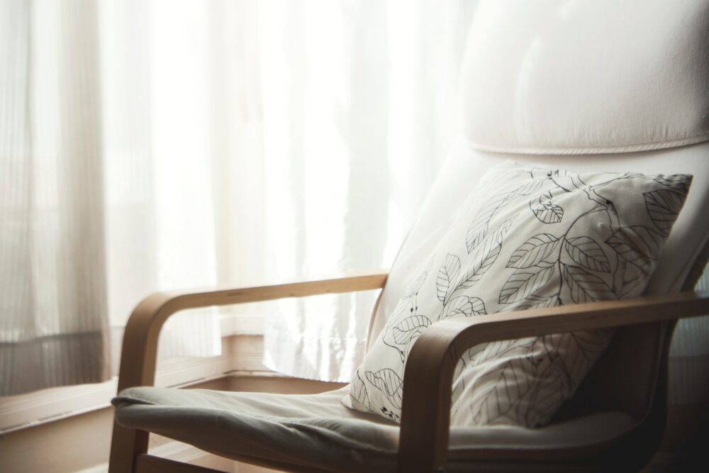 white and grey leaf-printed pillow on armchair
