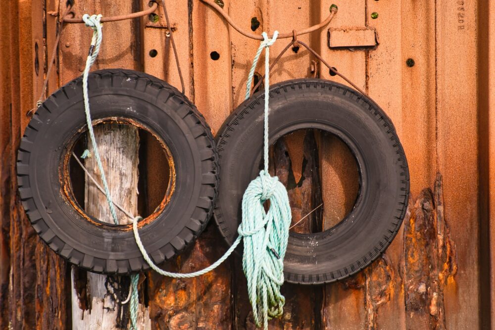 two old tires hanging on a rusty wall